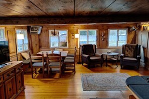 A wooden cabin interior with a dining table, chairs, a sofa, and a small round table. - Holiday home with 1 bedroom (St.Blasien \/ Menzenschwand)