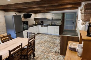 Une cuisine de taille réduite équipée d’un réfrigérateur, d’un four et d’une table à manger avec des chaises.