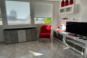 A modern living room with a flat-screen TV, a red chair, and a cabinet with drawers. - Holiday home in Chayofa with swimming pool (Chayofa)