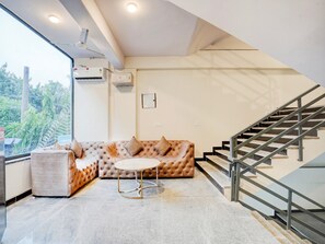 A modern living room with a sofa, a round coffee table, and a staircase. - Deluxe Preet Vihar Metro Station (New Delhi)