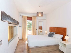A hotel room with a bed, bedside tables, a hanging lamp, and a view through a window. - Villa in Sa Pobla With Swimming Pool (Sa Pobla)