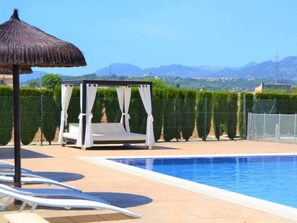 A pool area with a white canopy and lounge chairs, surrounded by a fence and a view of mountains. - Villa in Sa Pobla With Swimming Pool (Sa Pobla)