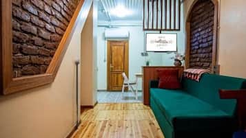 A hallway with wooden flooring, a green sofa, and a brick wall.