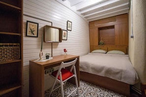 A compact bedroom with a wooden desk, a chair, a bed with a headboard, and a wall-mounted mirror. - Mercan Apartments Balat (Fatih)