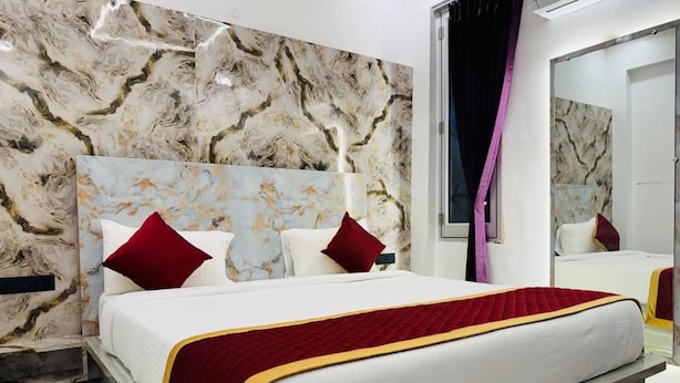 A modern hotel room with a marble-patterned wall, a large bed with a red and gold bedspread, and a large mirror. - SSB Residency (Tiruvannamalai)