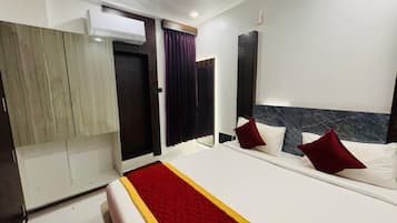 A hotel room with a bed, a wardrobe, an air conditioning unit, and a window with curtains.
