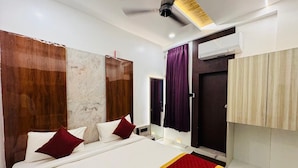 A hotel room with a large bed, a ceiling fan, and a wardrobe. - SSB Residency (Tiruvannamalai)