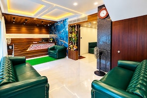 Un moderno vestíbulo de hotel con sofás de cuero, un mostrador de recepción, un reloj de pared y un arreglo de plantas decorativo.