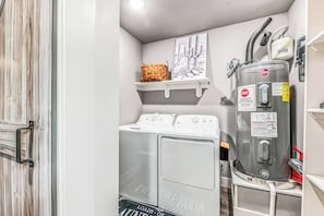 A compact laundry room with a washer, dryer, and a water heater.