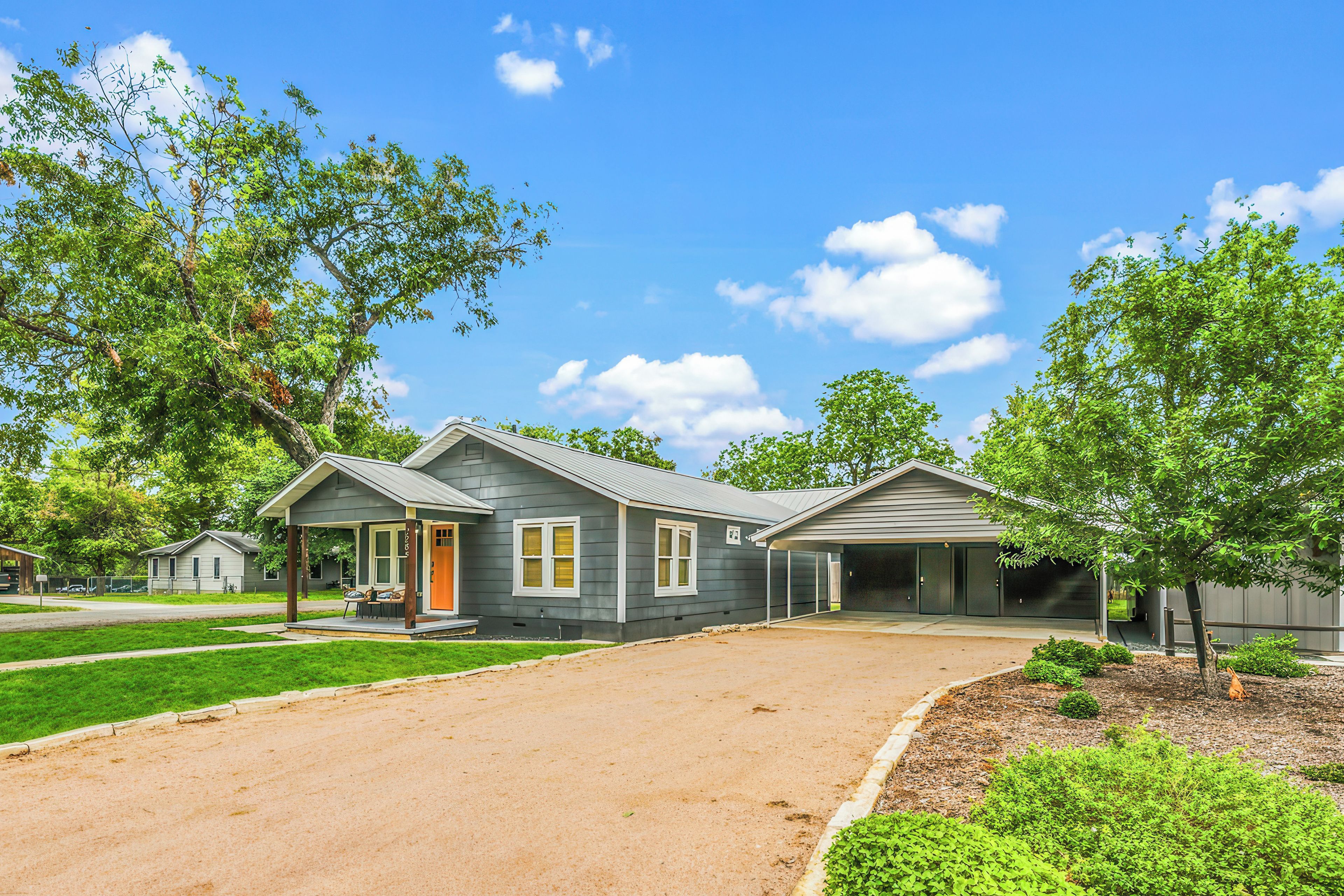 A residential property with a covered driveway, a front porch, and a garage.