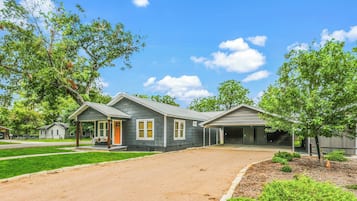 A residential property with a covered driveway, a front porch, and a garage.