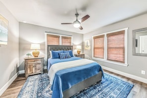 A bedroom with a bed, nightstands, a ceiling fan, and a window with blinds.