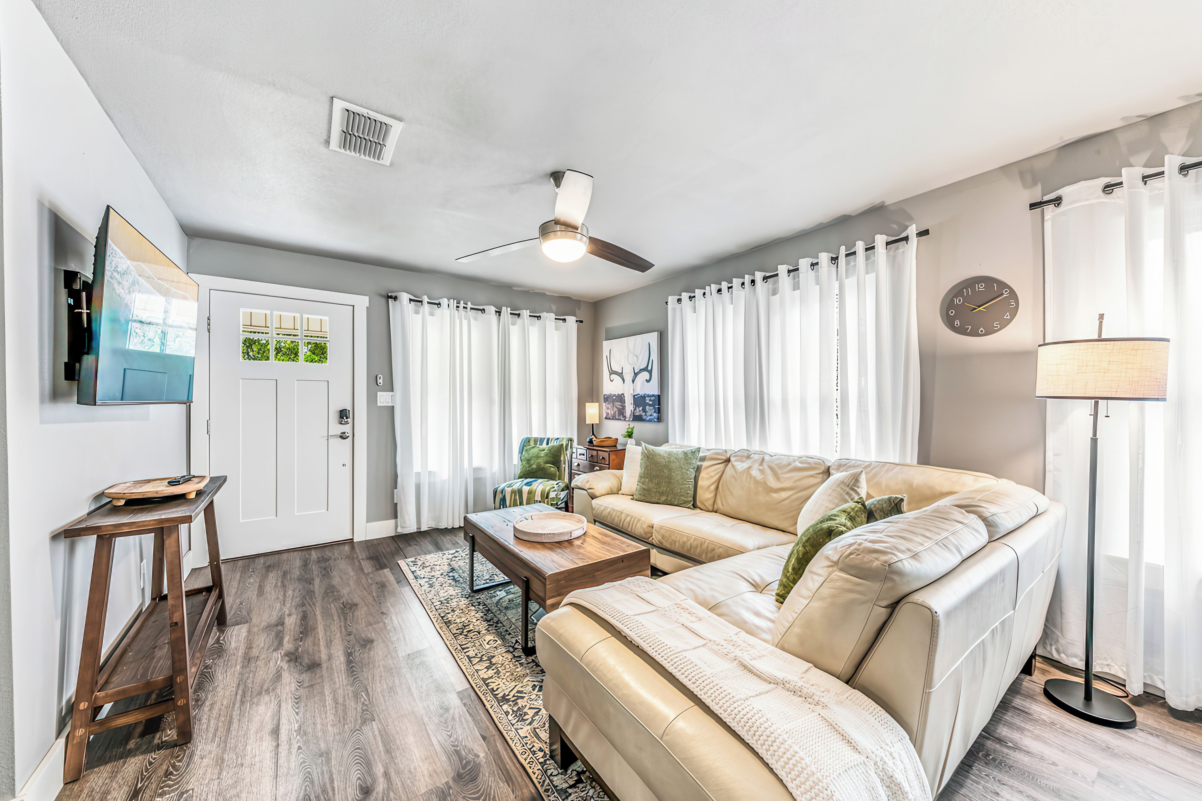 A living room with a sofa, a coffee table, a floor lamp, and a ceiling fan.