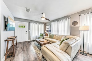 A living room with a sofa, a coffee table, a floor lamp, and a ceiling fan.