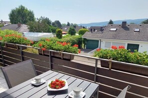 A balcony with a table set for two, a bowl of strawberries, and a cup of coffee. - Holiday apartment with 2 bedrooms (Gaienhofen-Horn)