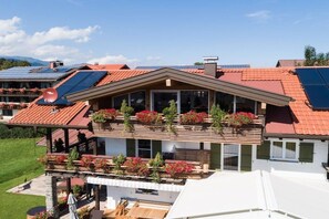 A multi-story house with a sloped roof, solar panels, and a balcony with flower boxes. - Apartment in Fischen with swimming pool (Fischen)