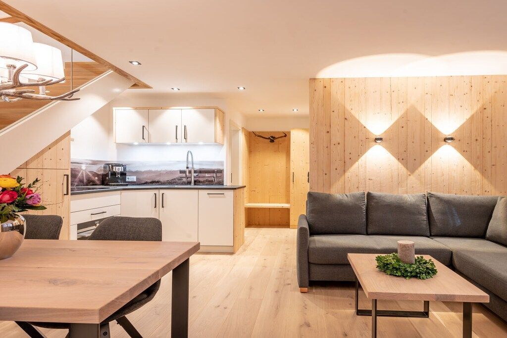 Un interno moderno con zona pranzo, cucina e un divano con un tavolino decorativo.