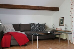 A living room with a sofa, a glass coffee table, and a red throw blanket. - 3 - Nina's Country House (Hohenschwangau)