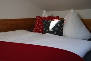 A bed with a white mattress, red and black pillows, and a wooden headboard. - 3 - Nina's Country House (Hohenschwangau)