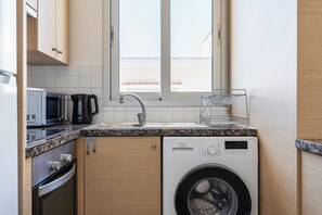 A compact kitchen with a washing machine, a microwave, and a coffee maker. - Modern Elegant UNIC Studio Suite (Egkomi Lefkosias)