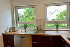 Eine Küche mit zwei Fenstern, einer Spüle, einem Toaster und einem Geschirrspüler.