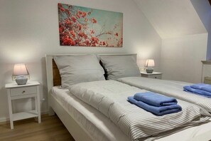 Ein Schlafzimmer mit zwei Betten, einem Nachttisch mit Lampe und einem Gemälde an der Wand.