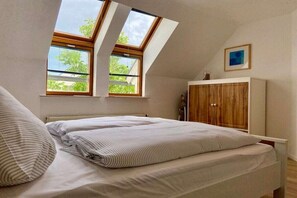 A bedroom with a bed, two skylights, a wooden wardrobe, and a framed picture on the wall. - Holiday apartment with 1 bedroom (Kressbronn)