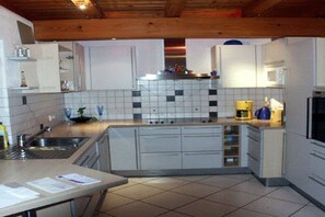 A kitchen with white cabinets, a tiled backsplash, a microwave, and a coffee maker. - Exclusive holiday home with pool (Berghaupten)