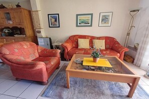A living room with a sofa, armchair, coffee table, and a small table with a plant. - Holiday home in Gruissan with swimming pool (Gruissan)
