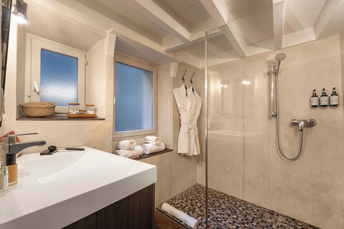 Une salle de bain moderne avec une douche à parois de verre, un lavabo blanc et une fenêtre donnant sur un beau paysage.