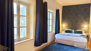 A bedroom with a bed, two bedside lamps, a window with shutters, and a dark curtain. - Room Porcelaine Chambéry (Chambéry)