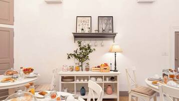 Een eetgedeelte met een ronde tafel, stoelen, een buffet en een wandplank met decoratieve objecten.