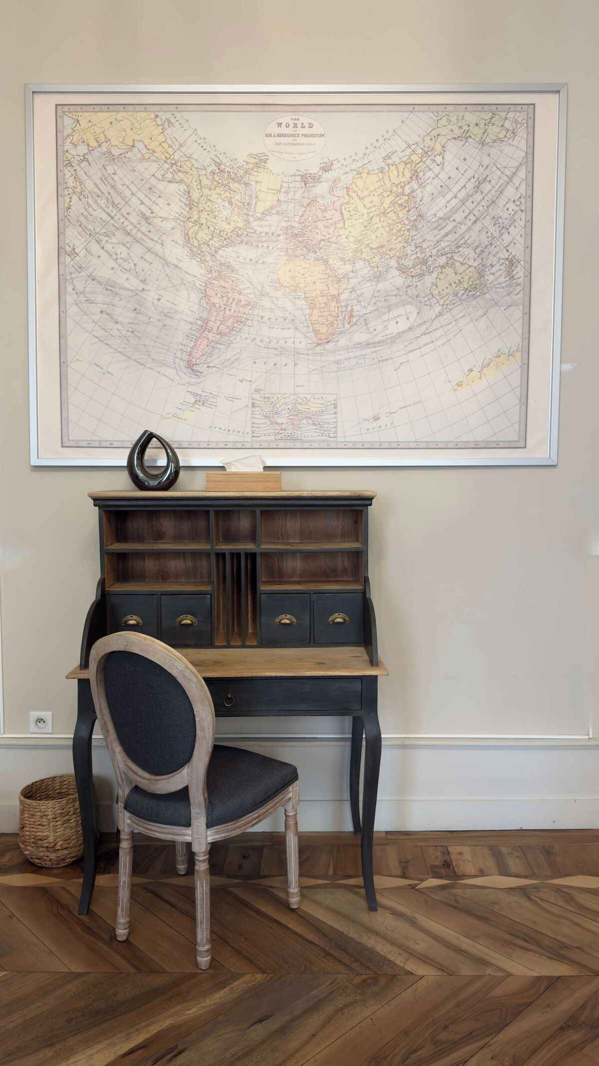 Quarto com escrivaninha, cadeira e um grande mapa-múndi na parede.