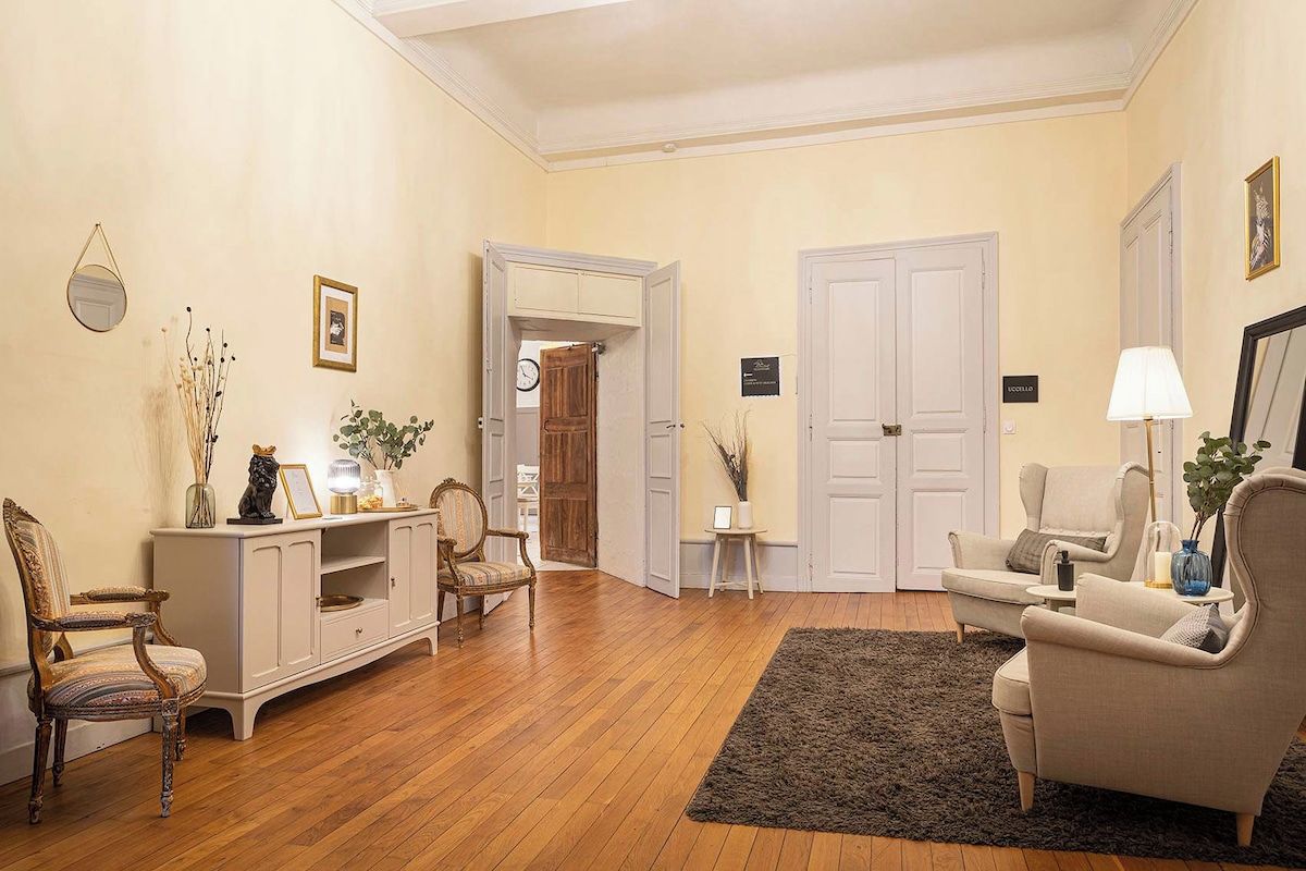 Sala de estar com piso de madeira, um rack branco e duas poltronas.