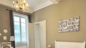 Habitació d'hotel amb un llit gran, una taula de treball, una cadira, un penjoll i un quadre a la paret.