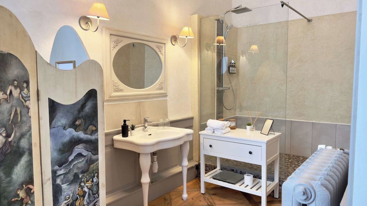 A bathroom with a sink, mirror, shower, and towel rack.