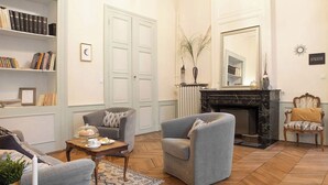 Un saló amb una llar de foc, una biblioteca i dues butaques.