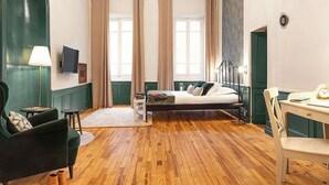 Ein Hotelzimmer mit Bett, Schreibtisch, Stuhl, Lampe und Fernseher.
