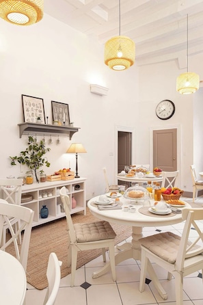 Een eetgedeelte met een ronde tafel, witte stoelen en een buffetopstelling.