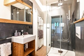 Ein modernes Badezimmer mit einer Duschkabine aus Glas, einem Holzbadezimmer-Möbelstück und einem großen Spiegel.