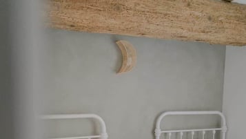 Een slaapkamer met twee bedden, een klein houten nachtkastje en een balken plafond.