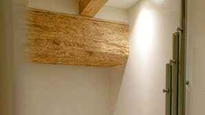Een badkamer met een wit bad, een douchegedeelte en een houten balk.
