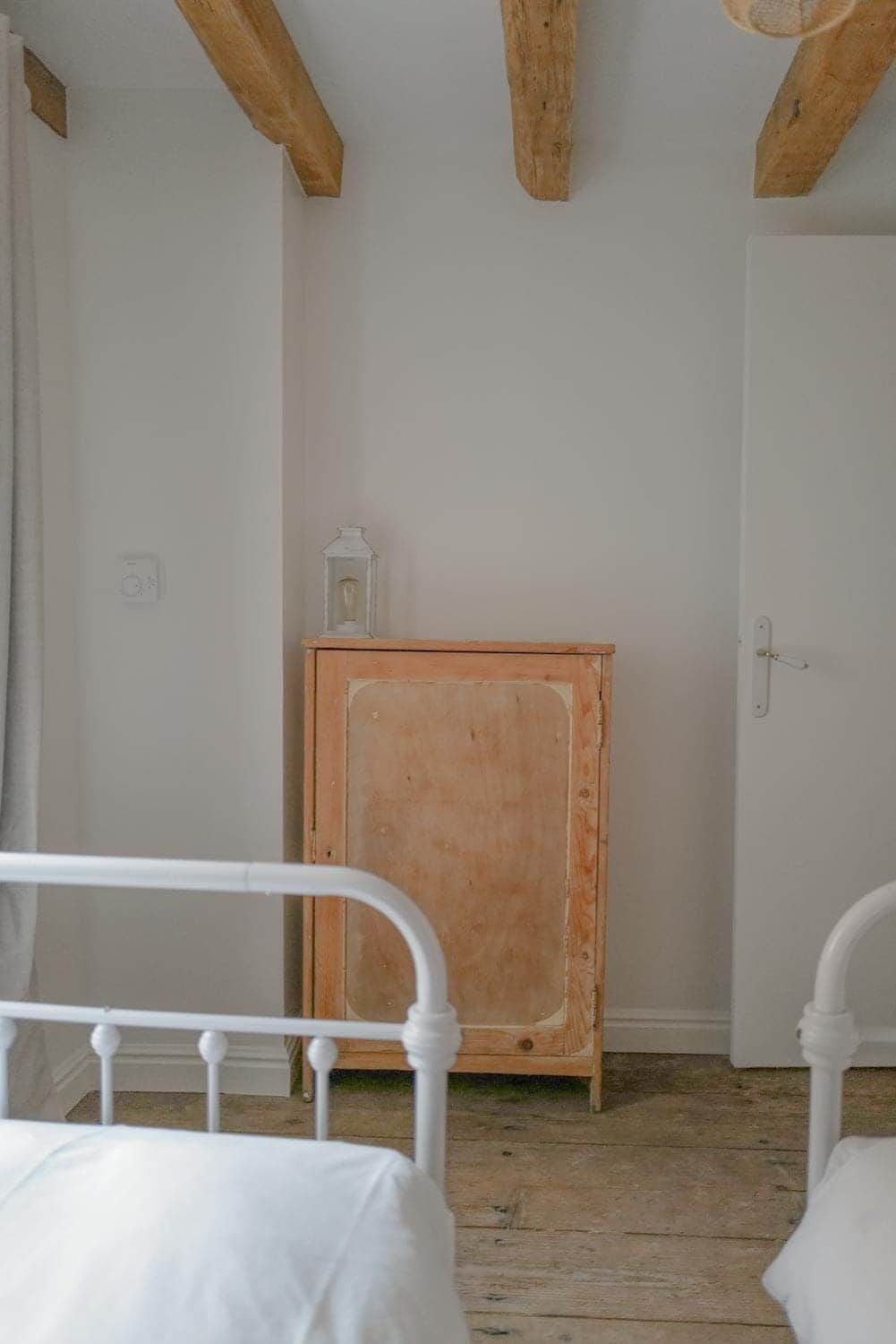 Ein Schlafzimmer mit zwei Betten, einem Holzschrank und einer weißen Tür.