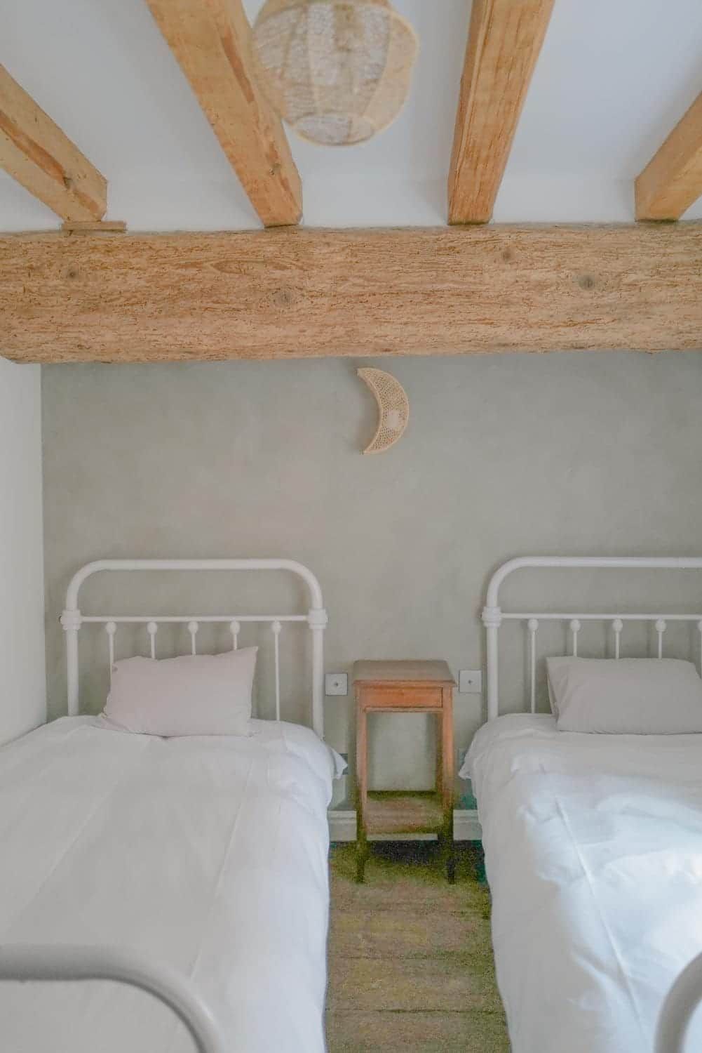 Une chambre avec deux lits, un plafond en bois et une petite table.