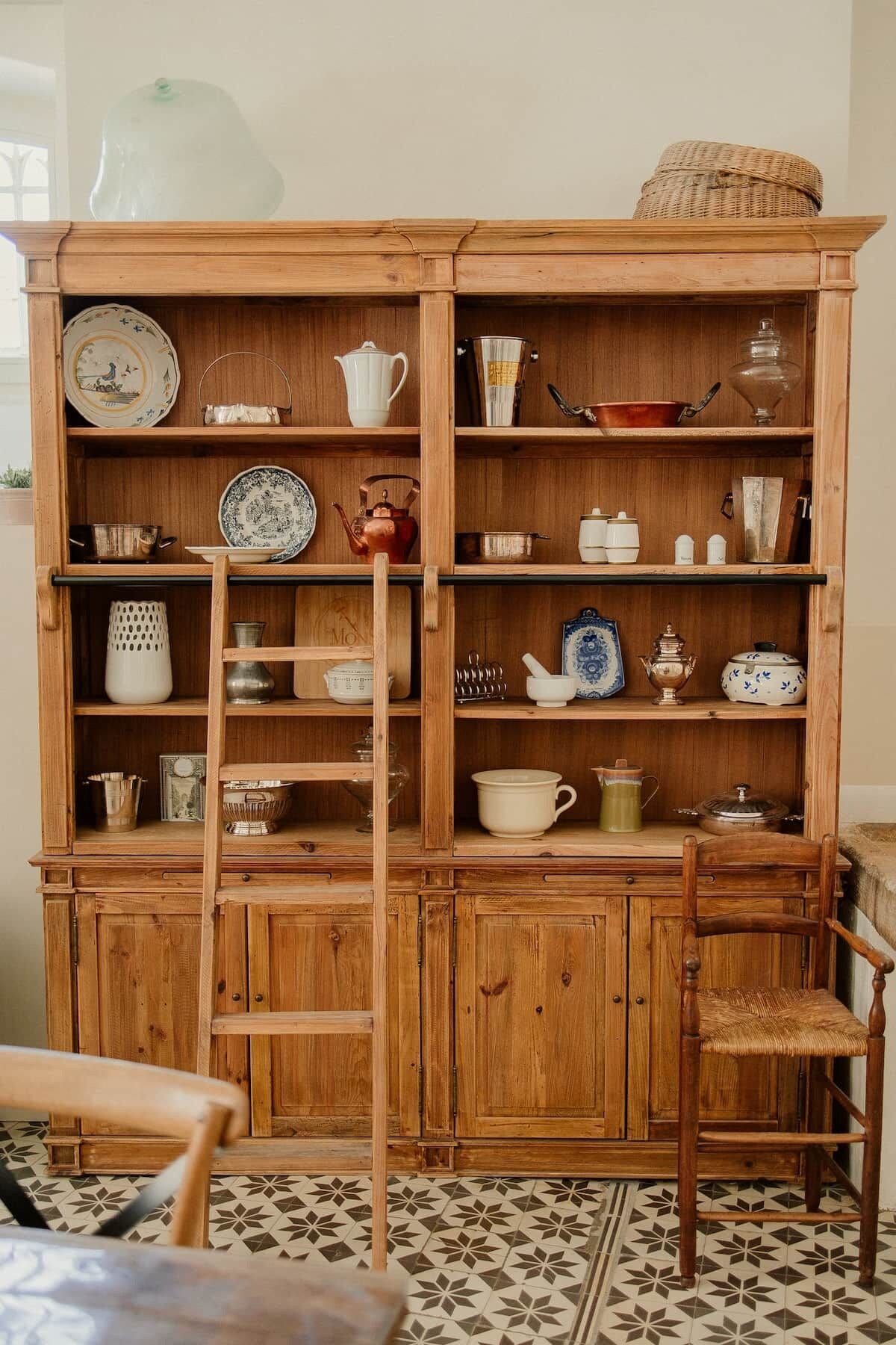 A wooden cabinet with multiple shelves containing various kitchenware items.