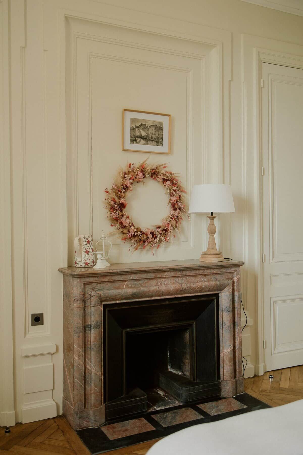 A room with a fireplace, a framed picture on the wall, and a decorative wreath.
