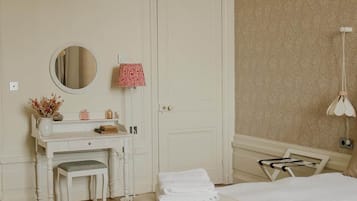 A bedroom with a bed, a bedside table, a mirror, a dresser, and a door.