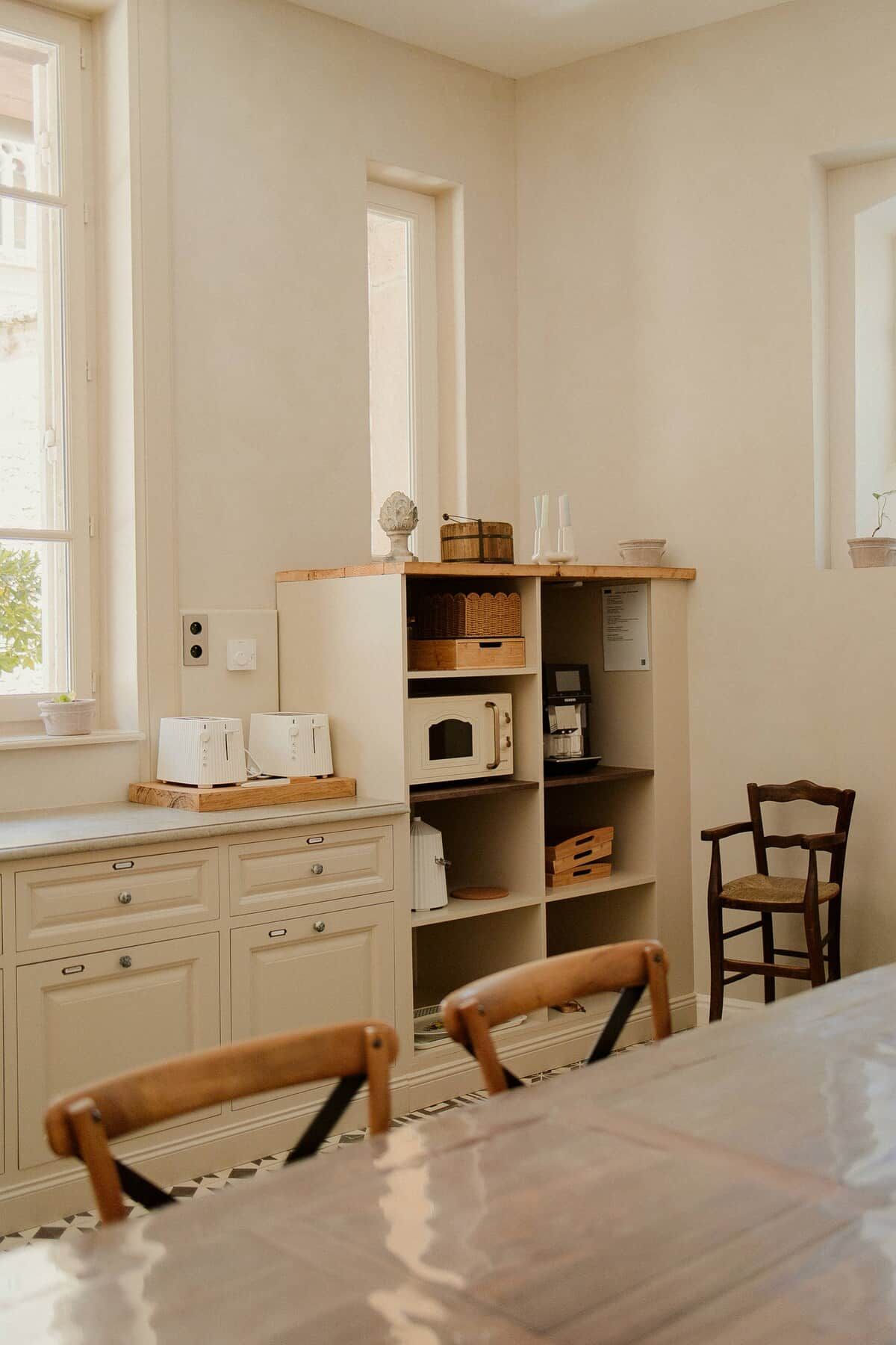 A kitchen with white cabinetry, a wooden countertop, and a dining table with chairs.