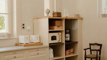 A kitchen with white cabinetry, a wooden countertop, and a dining table with chairs.