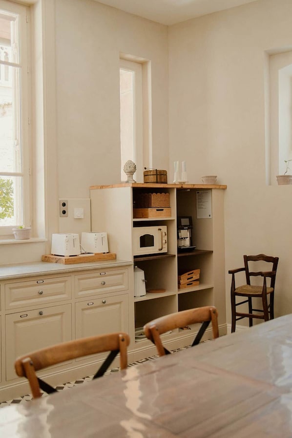 A kitchen with white cabinetry, a wooden countertop, and a dining table with chairs.
